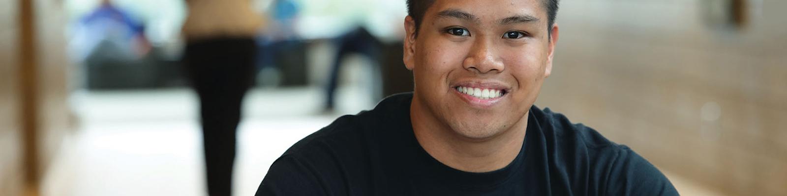 Smiling male student at a study table at Southeast Tech with an open binder in front of him.